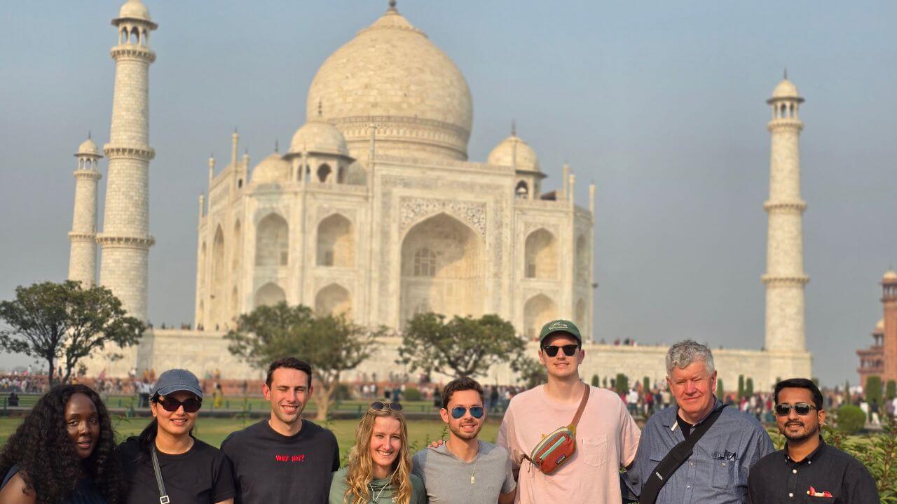 A group of international tourists posing in front of the Taj Mahal during a same day tour from Bangalore to Agra.