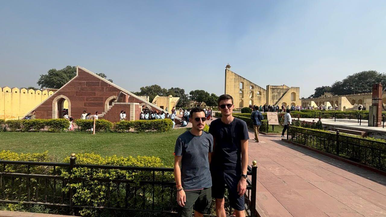 Two travelers standing inside Jantar Mantar in Jaipur during the 08 Days Golden Triangle Tour With Udaipur, with historic astronomical instruments in the background.