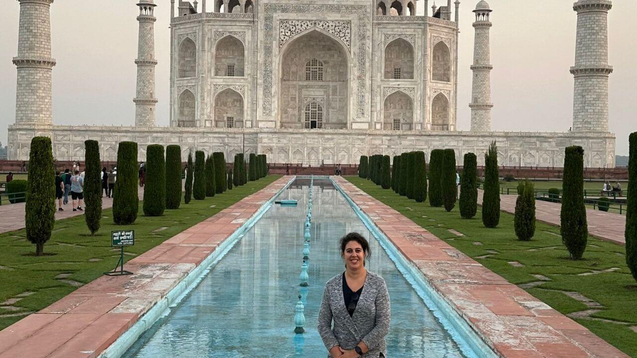 Female traveler standing in front of the Taj Mahal at sunrise during the Same Day Taj Mahal and Agra Fort Tour from Pune.